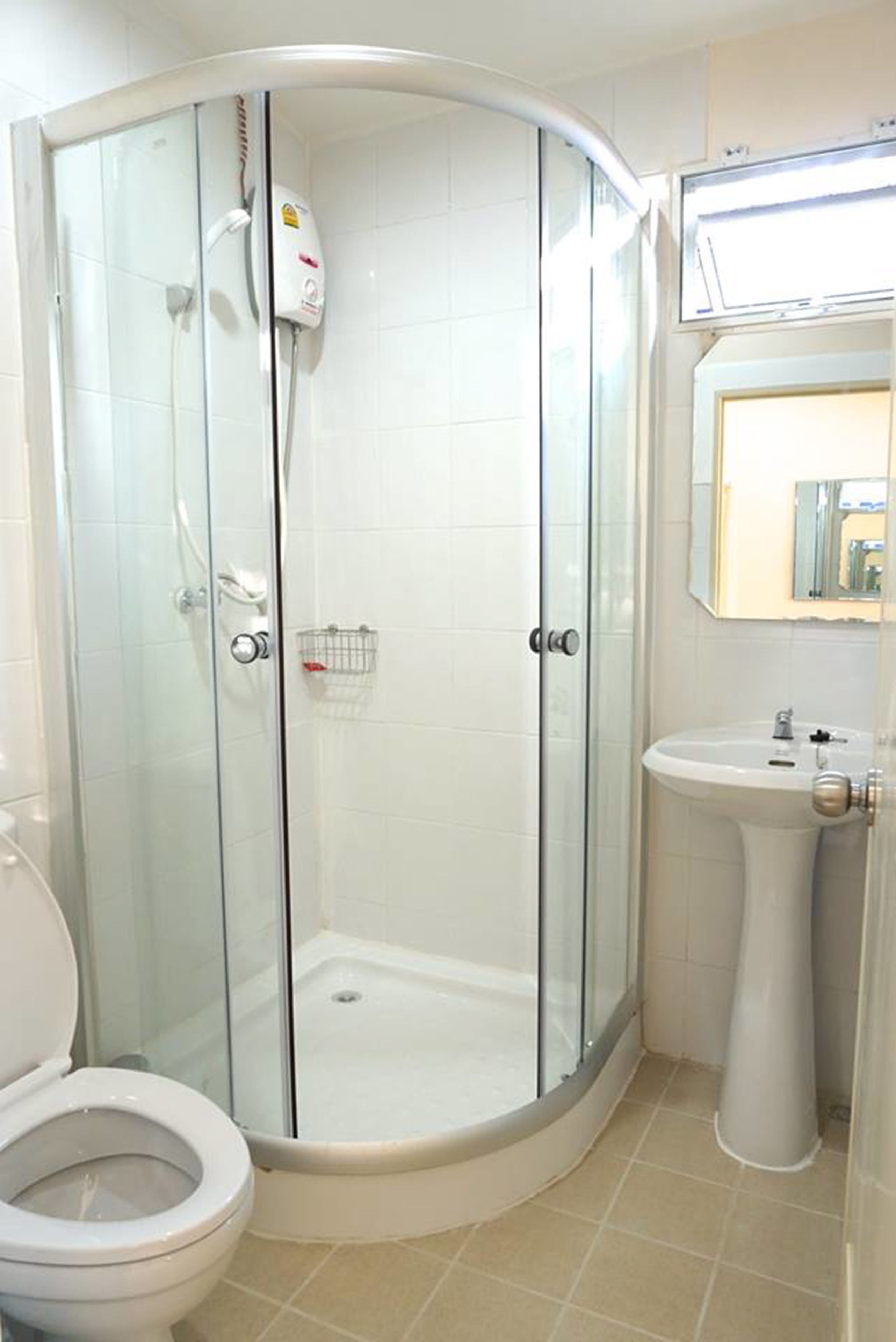 A bathroom with a glass-enclosed shower, a white sink, and a toilet.