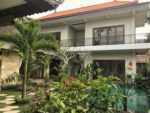 A two-story house with a balcony, a swimming pool, and various plants. - Umah Diuma (Ubud)