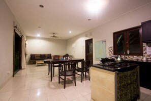 A kitchen with a dining area, a ceiling fan, and a map on the wall. - Umah Diuma (Ubud)