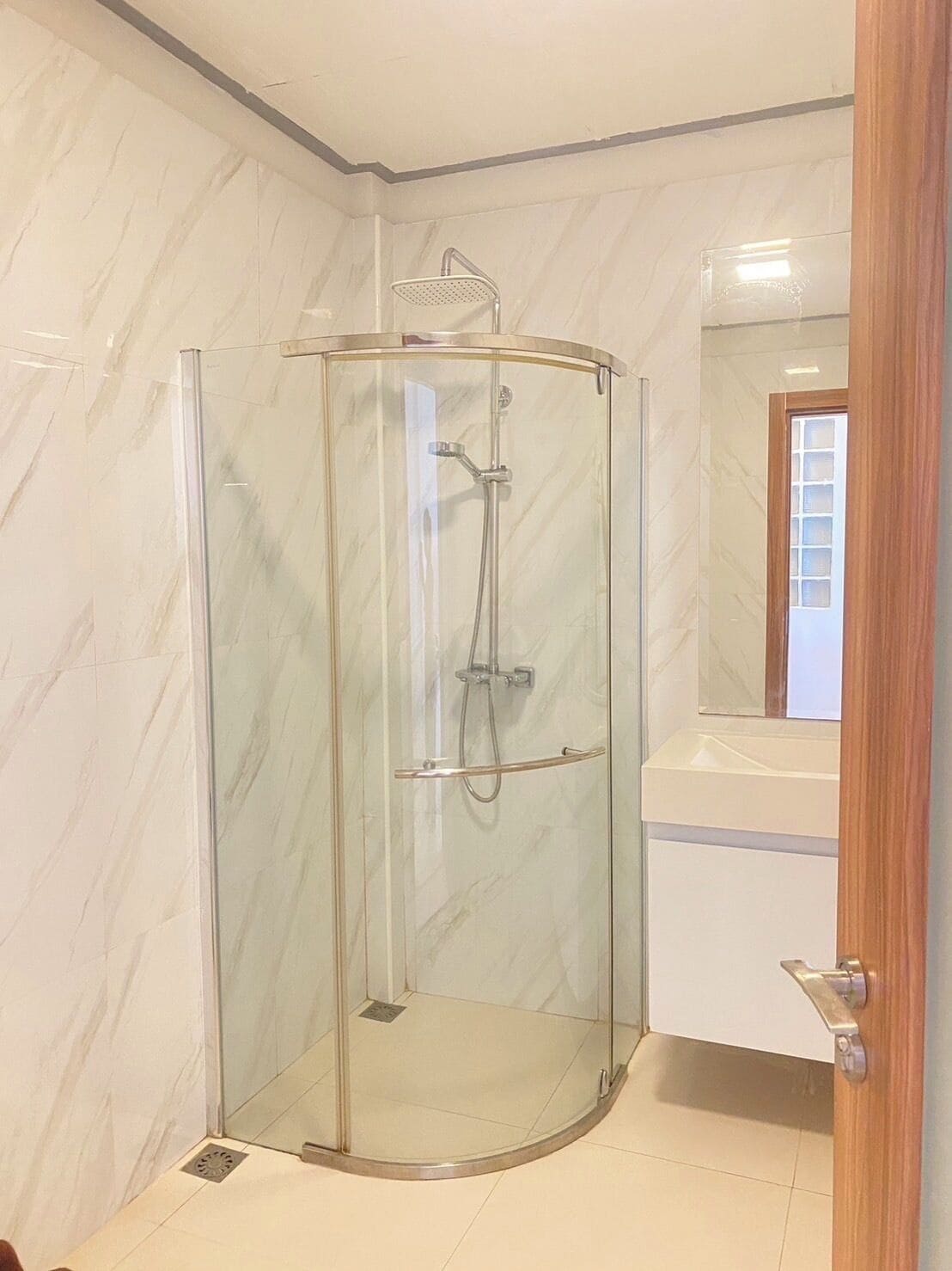 A glass-enclosed shower stall with a handheld showerhead and a fixed overhead showerhead.