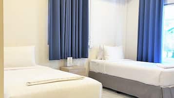 A hotel room with two beds, a nightstand, and a large window with blue curtains.