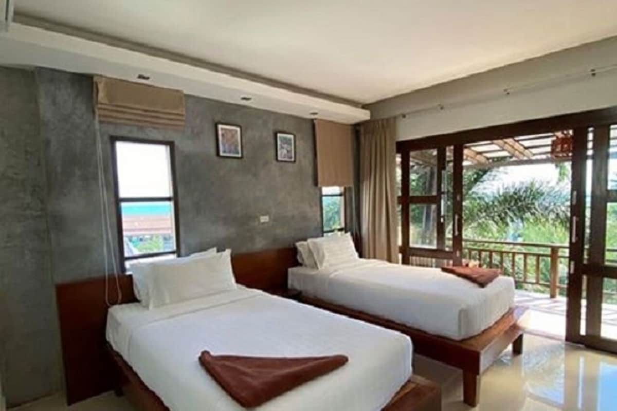 A hotel room with two beds, a large window, and a view of the outdoors.