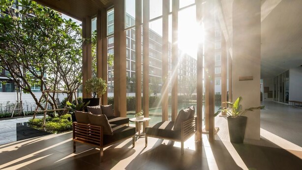 A modern indoor space with large windows, a seating area with a sofa and armchairs, and a potted plant. - Marine Room At Baan Khun Koey Hua Hin (Hua Hin)