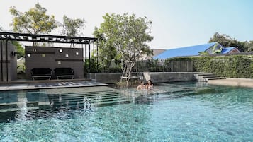 Una piscina al aire libre, sillones reclinables de piscina