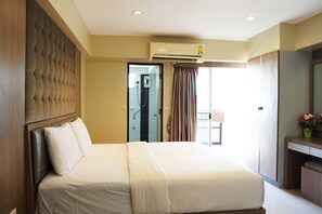 Une chambre d’hôtel avec un grand lit, une tête de lit en bois, une armoire intégrée, une salle de bain avec douche et un grand miroir.
