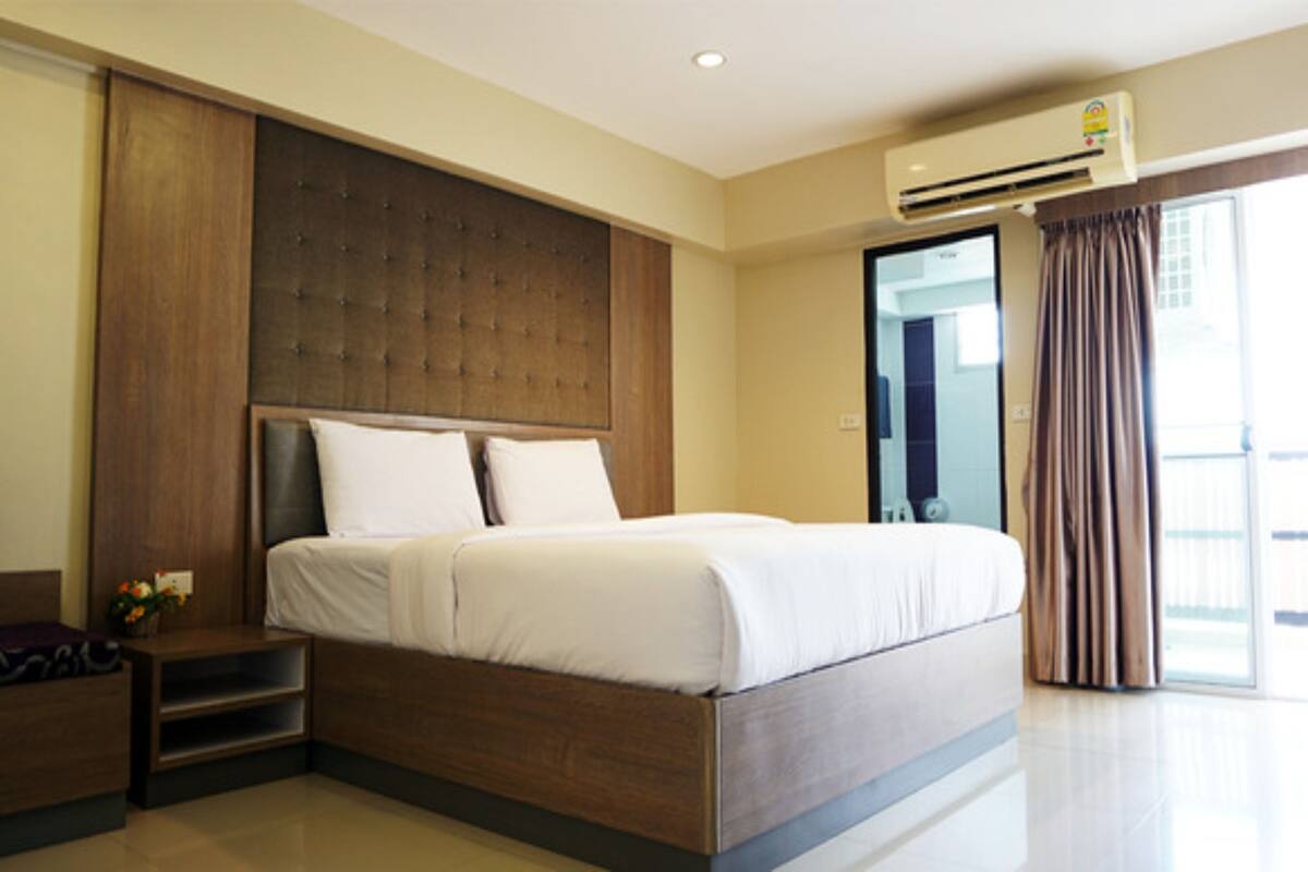 Een moderne hotelkamer met een groot bed, een houten hoofdbord, een nachtkastje en uitzicht door een groot raam.