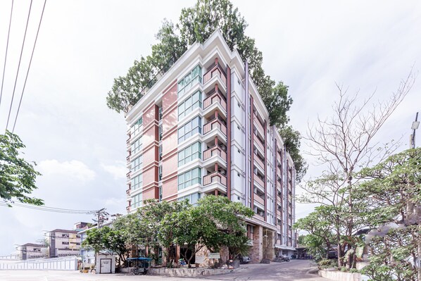 Un hôtel à plusieurs étages doté de balcons, d’un parking et entouré de verdure.
