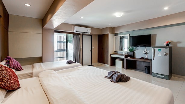 A hotel room with two beds, a desk, a refrigerator, and a window with curtains. - Latin Garden (Bangkok)