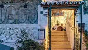 Una escalera que lleva a una puerta con una reja metálica, decorada con luces de cadena.