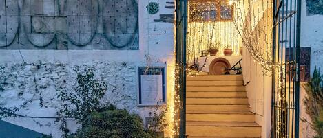 Un escalier menant à une porte surmontée d’un portail en métal, le tout décoré de guirlandes lumineuses.