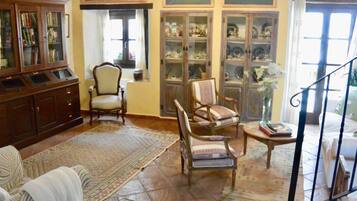 Quarto tradicional com um armário de madeira, duas poltronas, uma pequena mesa e uma estante de livros.