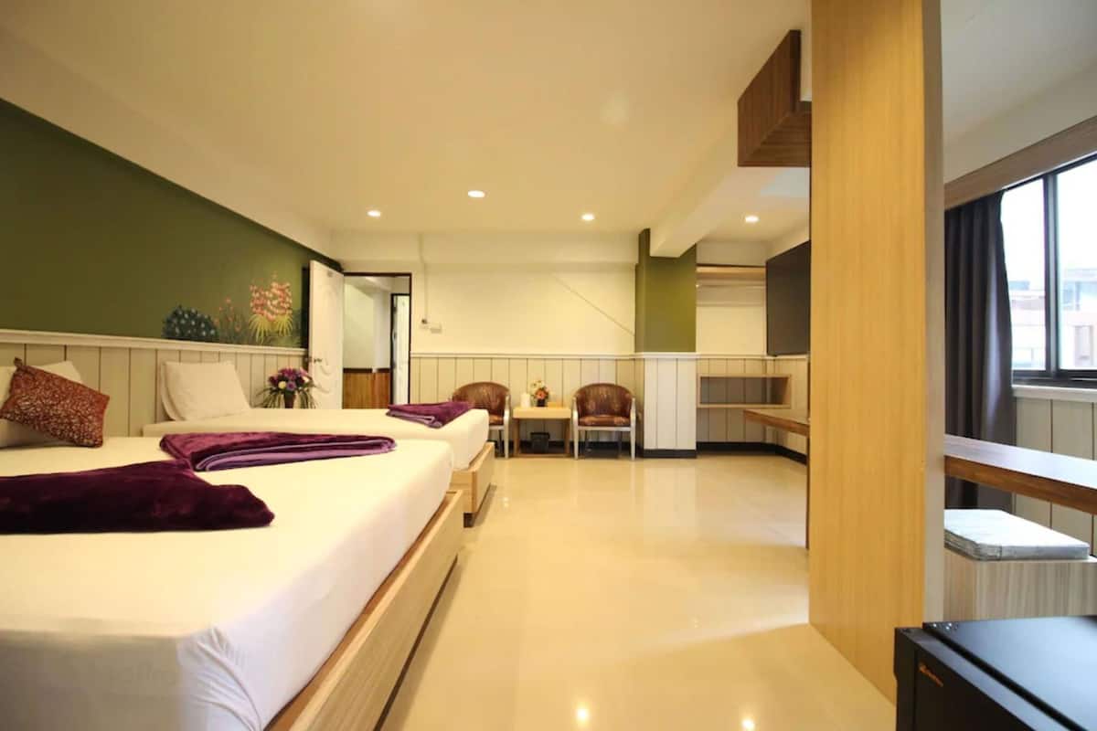 A modern hotel room with a large bed, a small table, a chair, and a view of the city through the window.