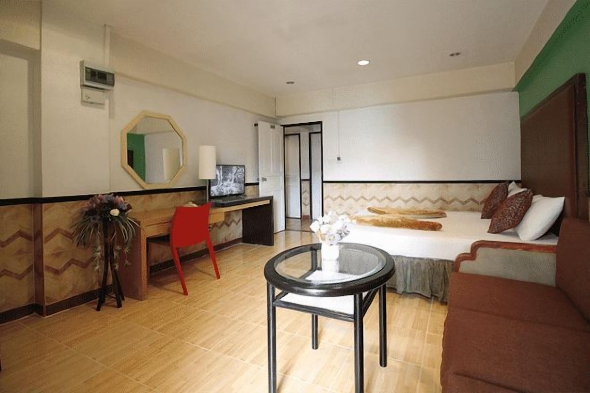 Une chambre d’hôtel comprenant un lit, un bureau, une chaise, une petite table et un miroir.