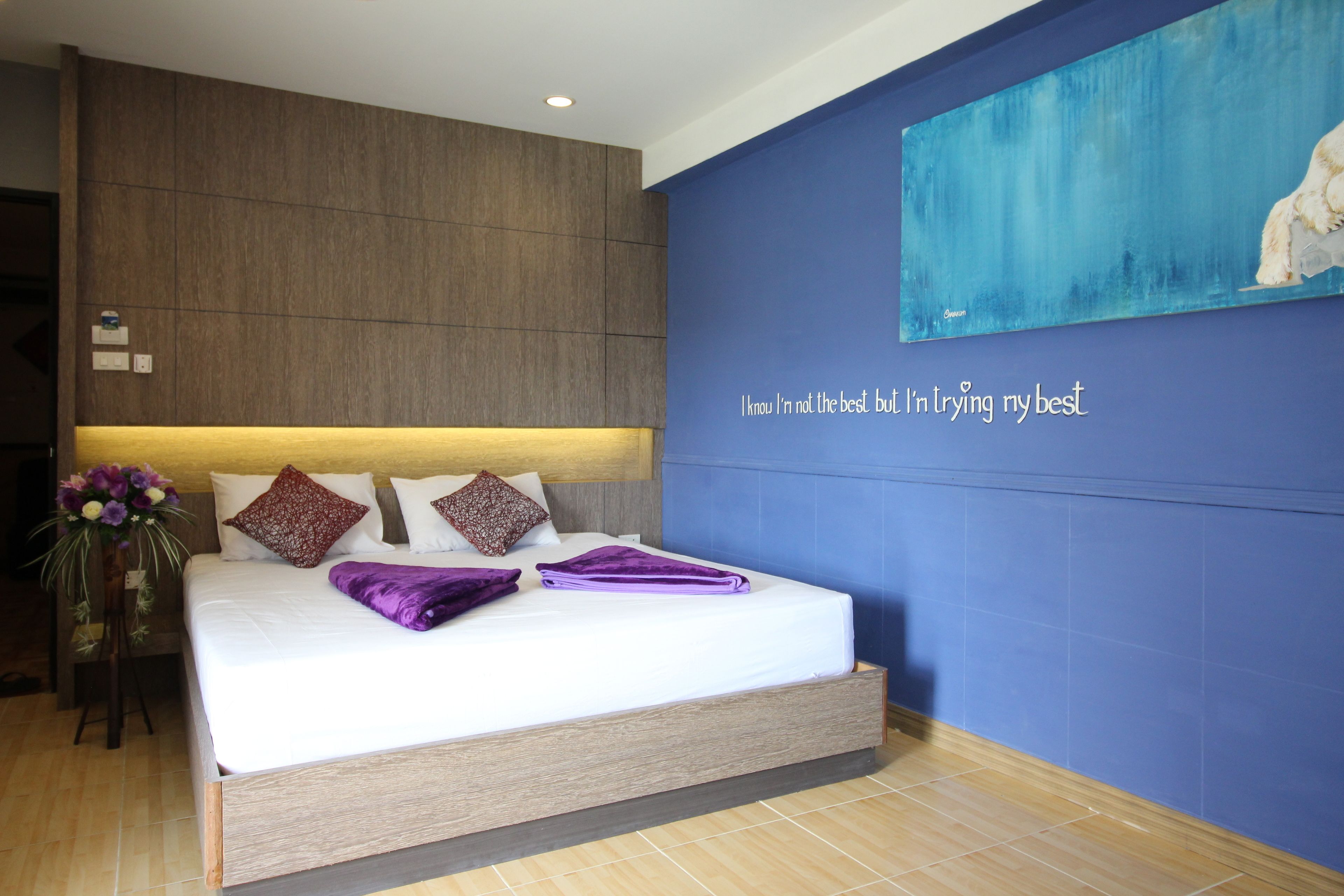 Un dormitorio moderno con una cama grande, una pared de acento azul y una frase motivacional.