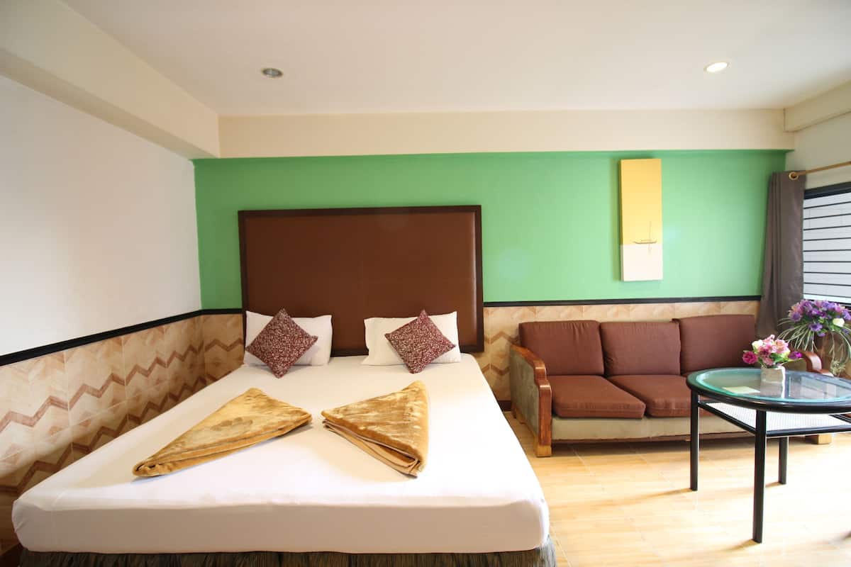 A hotel room with a bed, a sofa, and a small table with flowers.