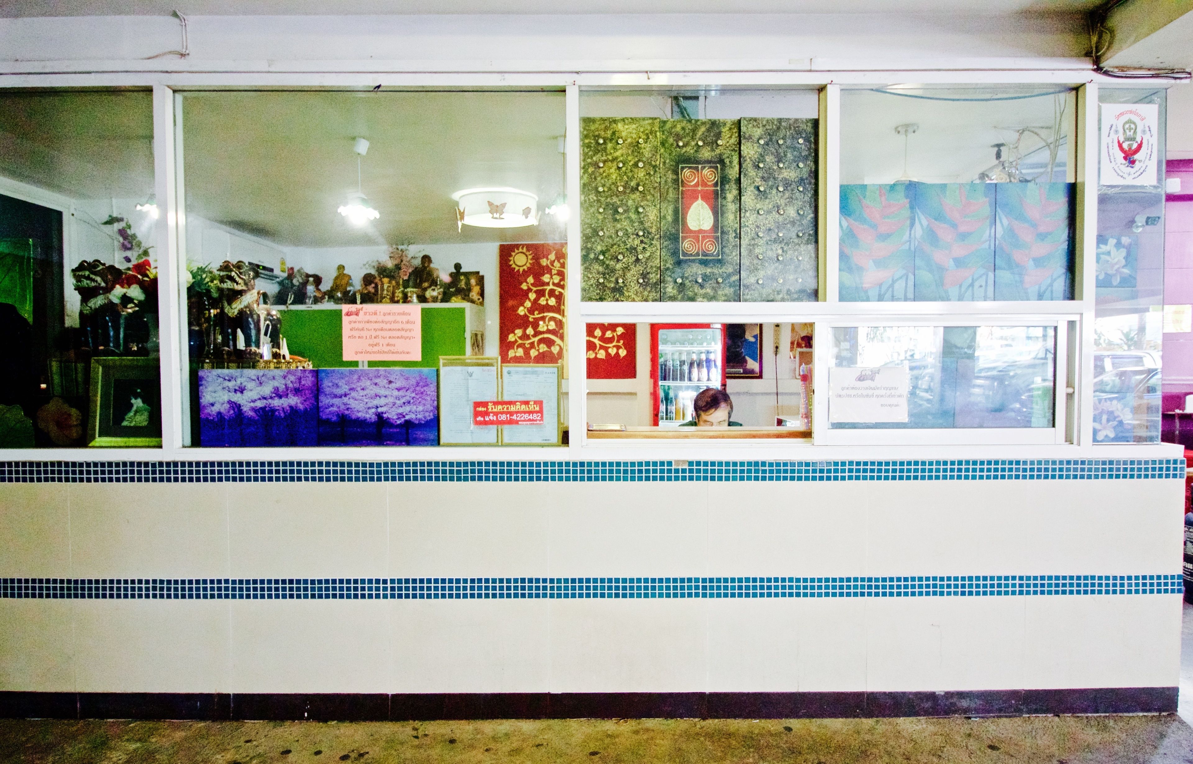Une devanture de magasin ornée d’une bordure de carreaux, de divers panneaux et d’une vitrine.