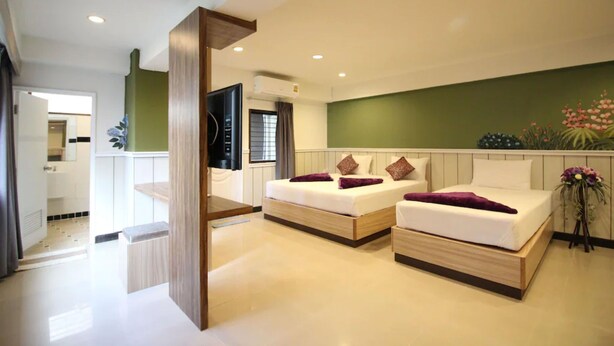 A modern hotel room with two beds, a TV, and a green accent wall. - Kaya Place (Bangkok)