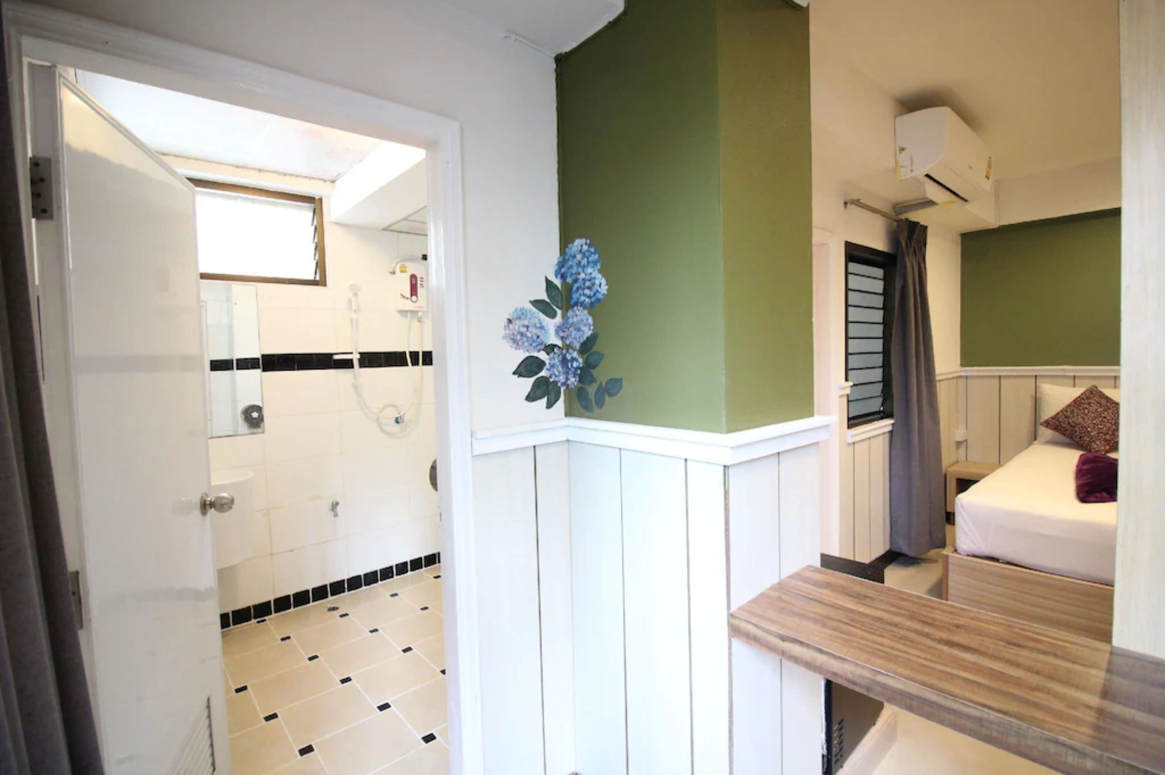 Habitación de hotel con baño, una ventana pequeña, una cama con almohada y un banco de madera.
