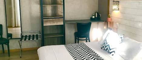 Un dormitorio con cama, escritorio, silla, escalera, espejo y ventilador de techo.