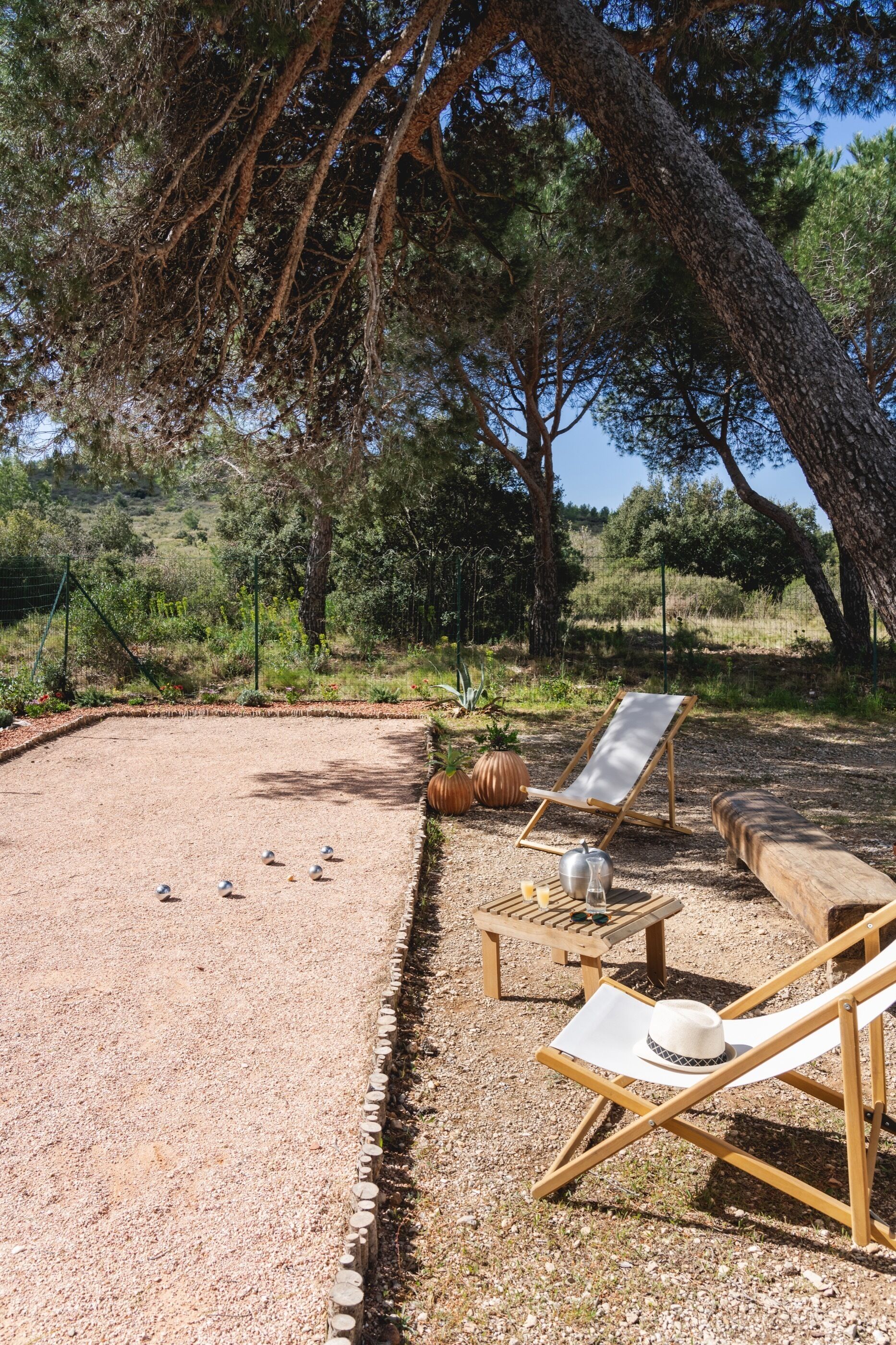 A gravel area with a pool table, two lounge chairs, and a hat on one of the chairs.