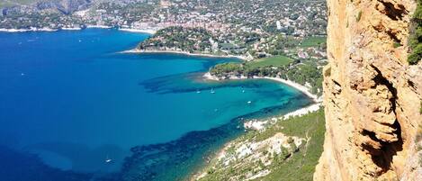 A coastal town with a clear view of the sea, a rocky cliff, and a densely built area with buildings.