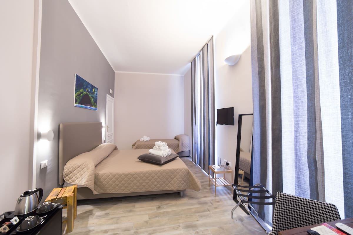 A modern hotel room with a bed, bedside table, and a flat-screen TV.