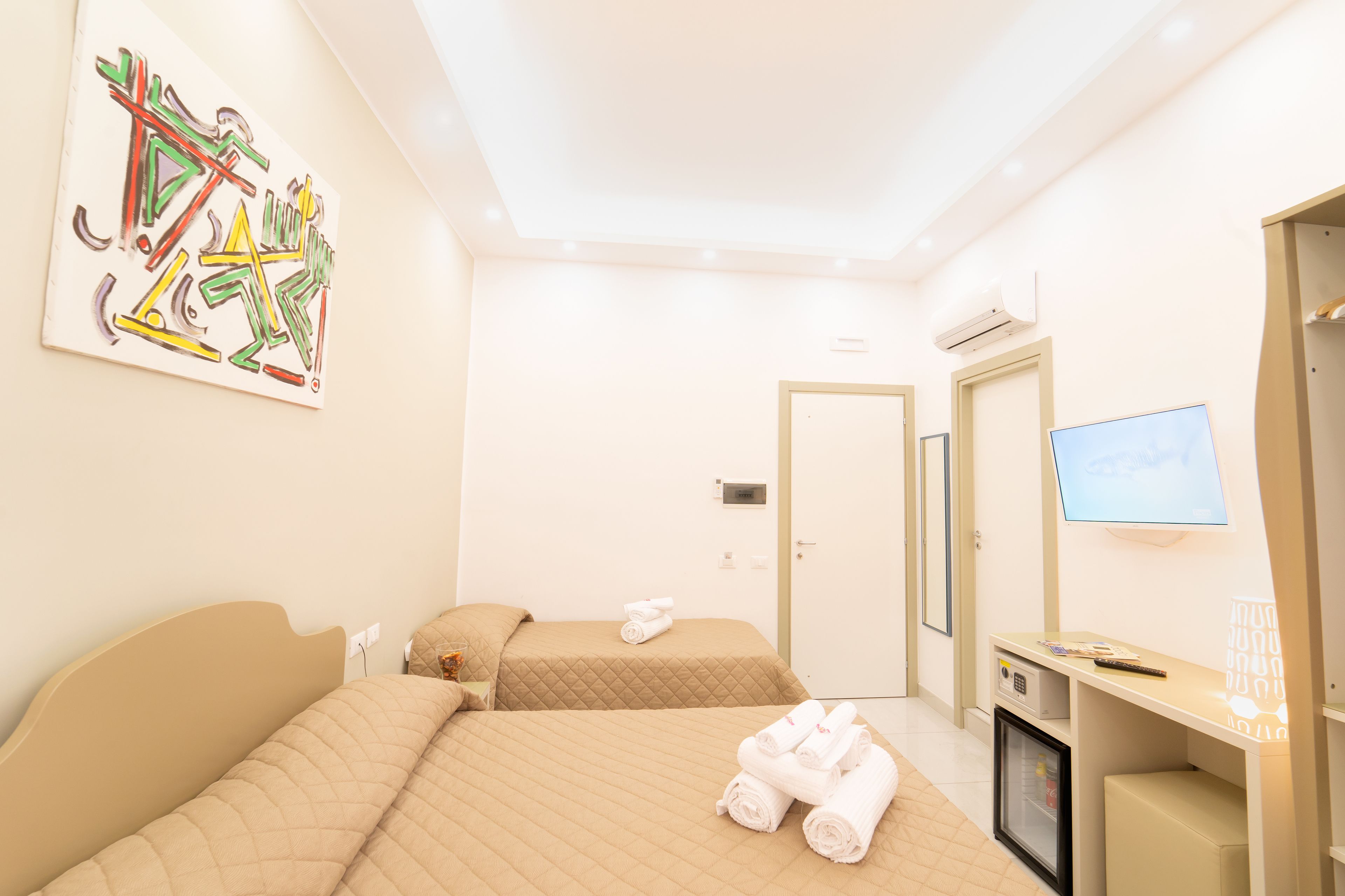 A hotel room with two beds, a television, a desk, and a minibar.