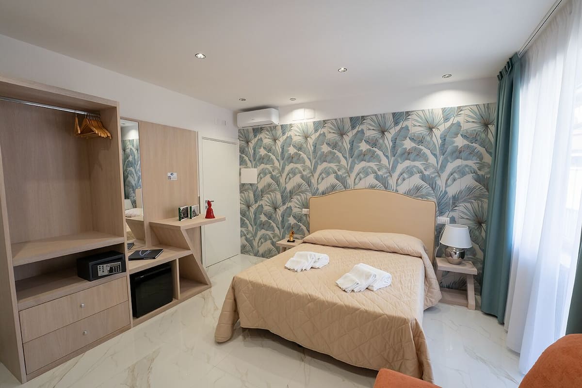 A hotel room with a bed, a wardrobe, a desk, and a nightstand.