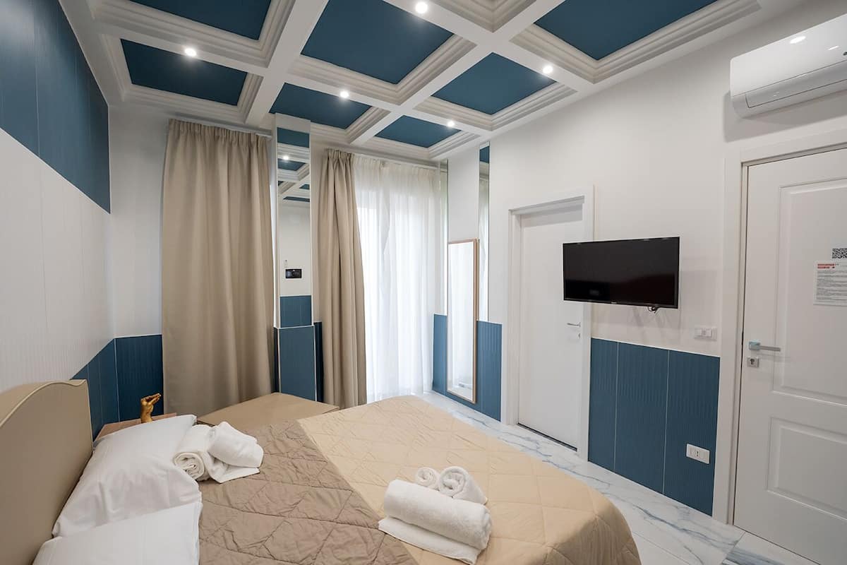 A hotel room with a bed, a TV mounted on the wall, and a door.