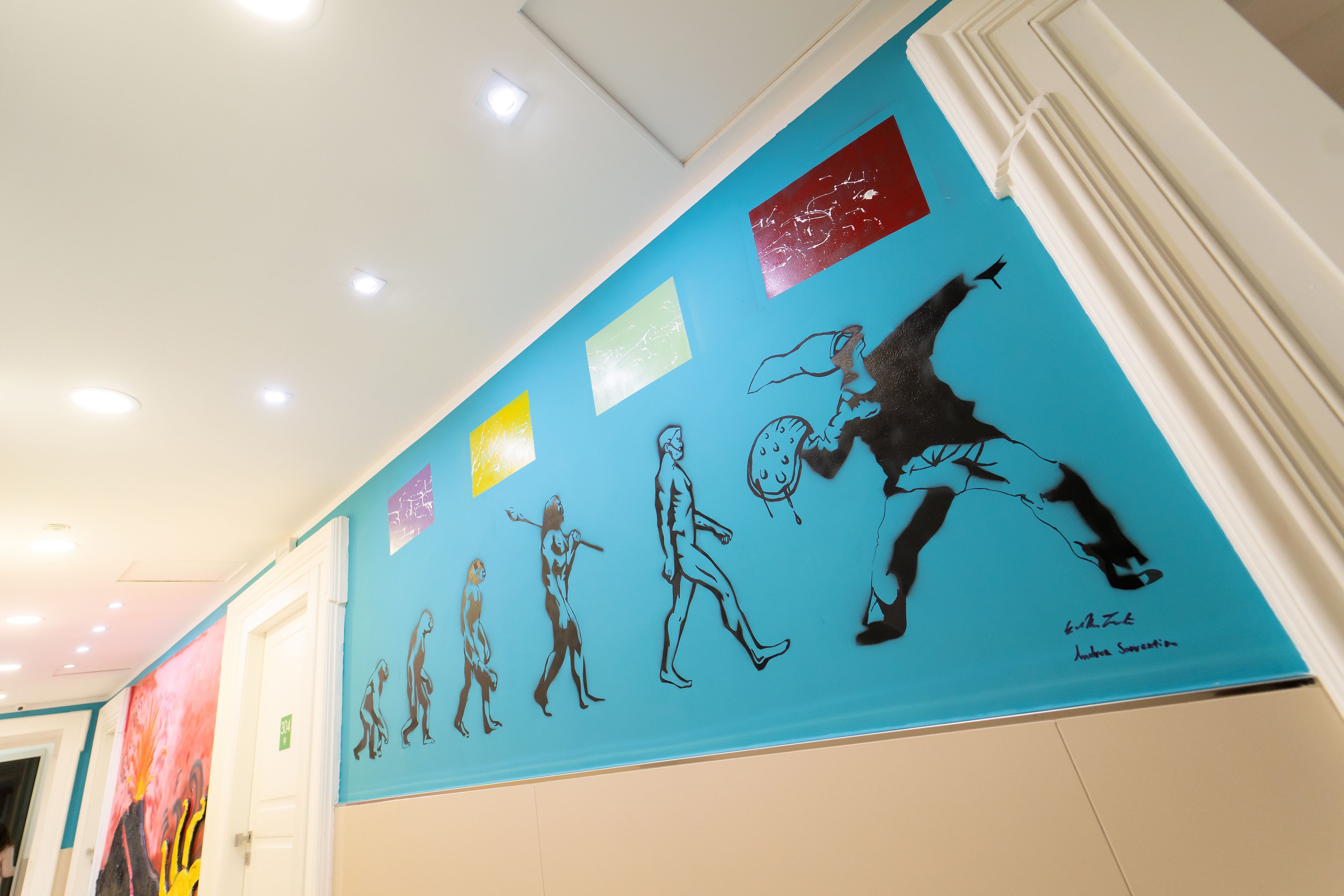 Un pasillo con una pared azul que presenta una línea de tiempo de la evolución humana.