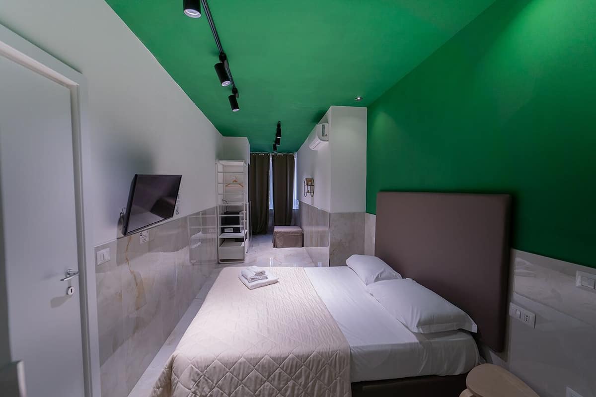 A hotel room with a bed, a TV, a wardrobe, and a bathroom.