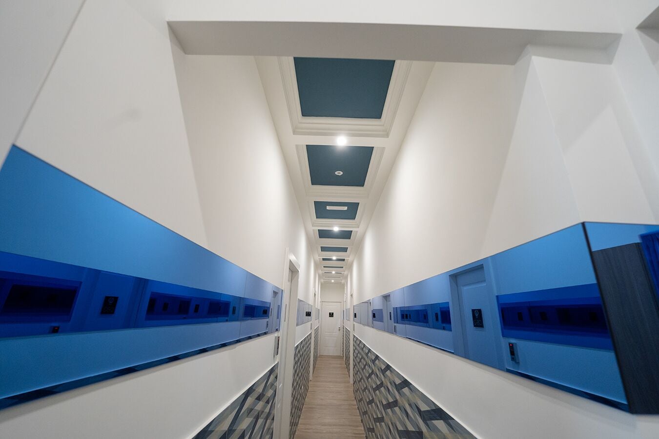 A hotel hallway with blue lockers on both sides and a patterned floor.