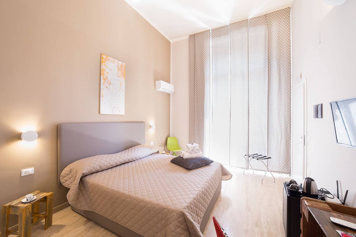 A modern bedroom with a large bed, a desk, and a chair.
