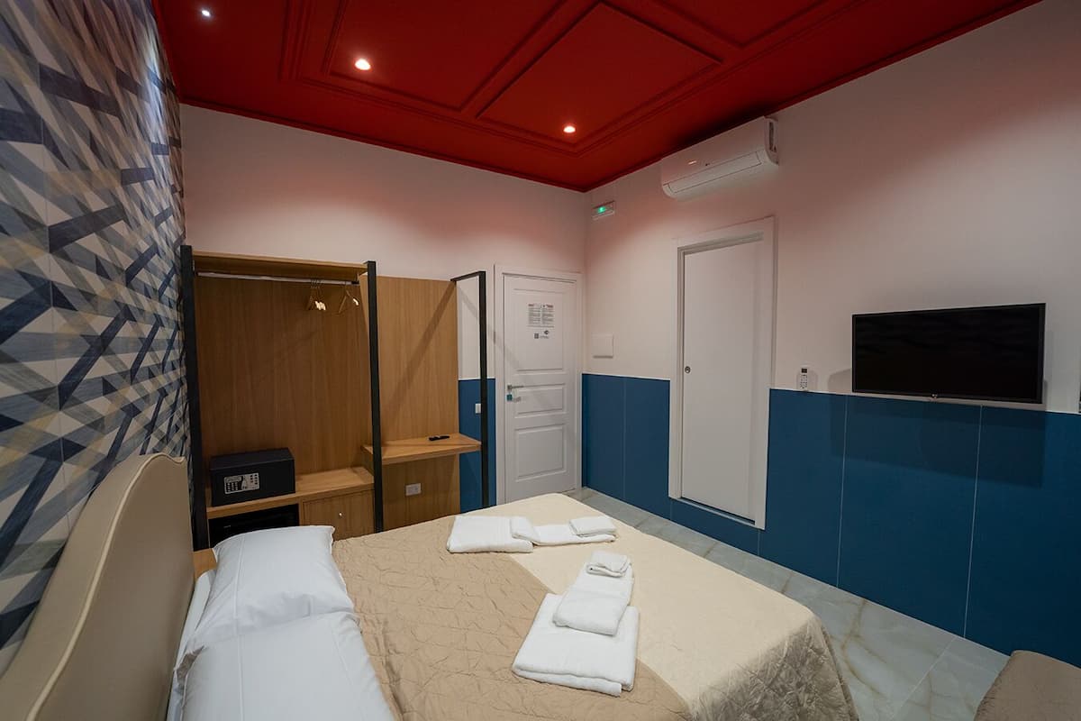 A hotel room with a bed, a wardrobe, a TV, and a shower area.
