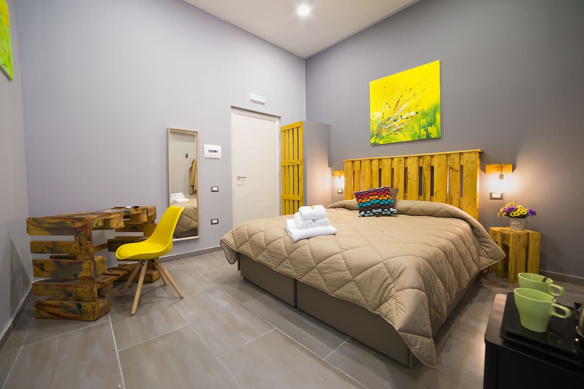 Ein Schlafzimmer mit einem Bett, einem Schreibtisch, einem Stuhl und einem kleinen Tisch mit Blumen.