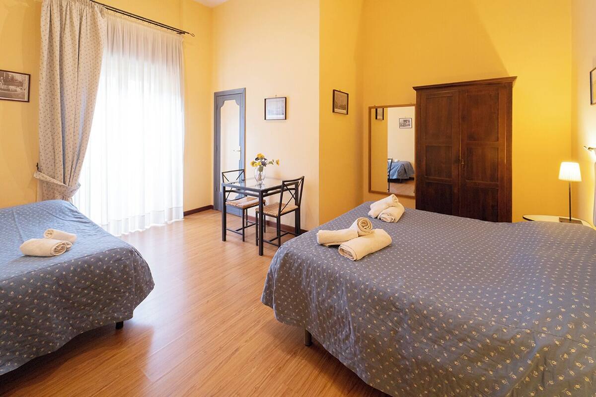 Ein Hotelzimmer mit zwei Betten, einem Schreibtisch mit Stuhl, einem Spiegel und einem Kleiderschrank.
