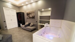 Een moderne badkamer met een groot bad, een grijze bank en een kapstok.