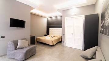 A modern bedroom with a bed, a sofa, a TV, and a door.