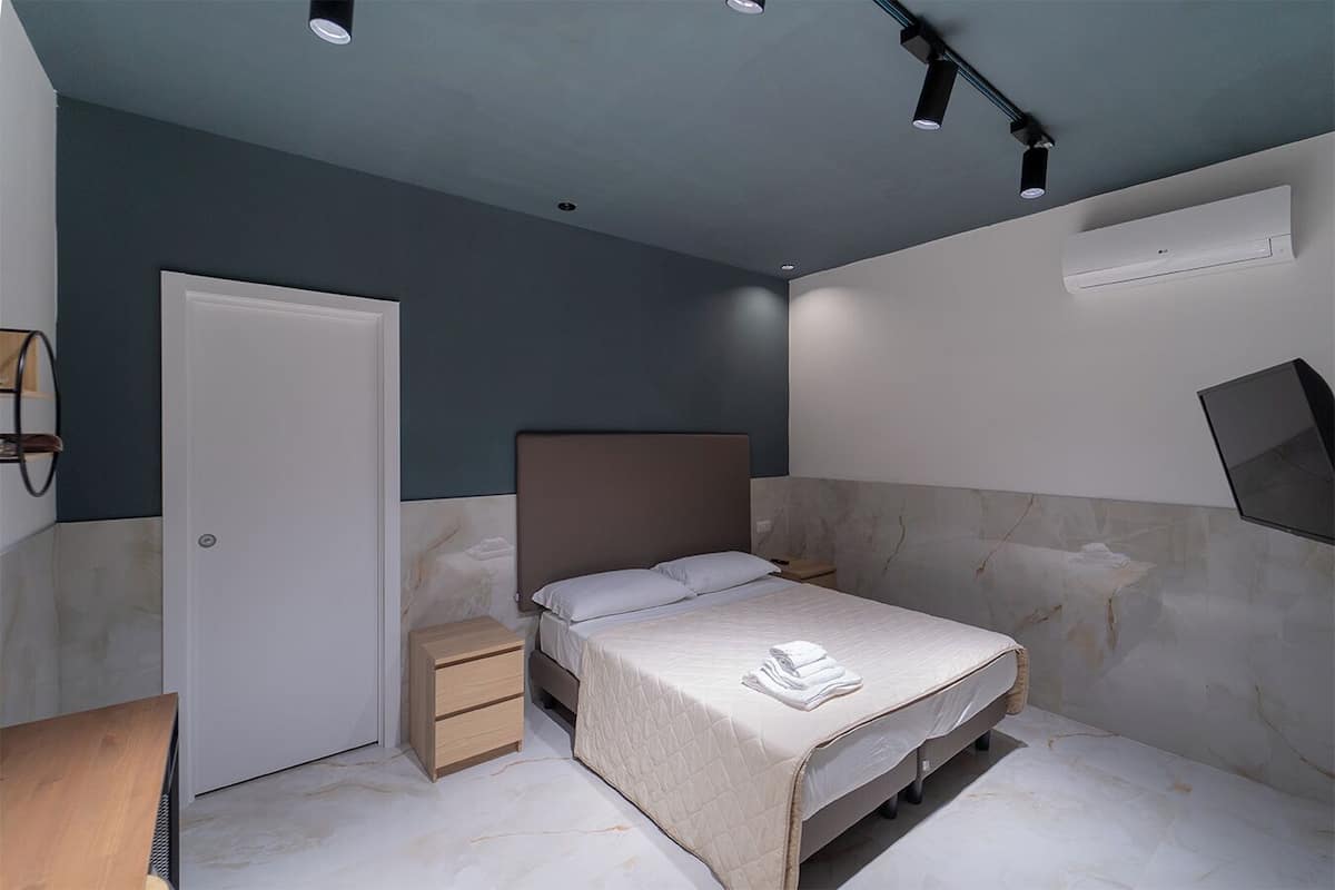 Ein modernes Schlafzimmer mit Bett, Nachttischen, einem Kleiderschrank und einer Deckenleuchte.