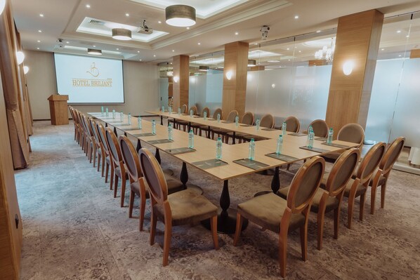 Un salón de conferencias con una larga mesa, sillas y un atril.