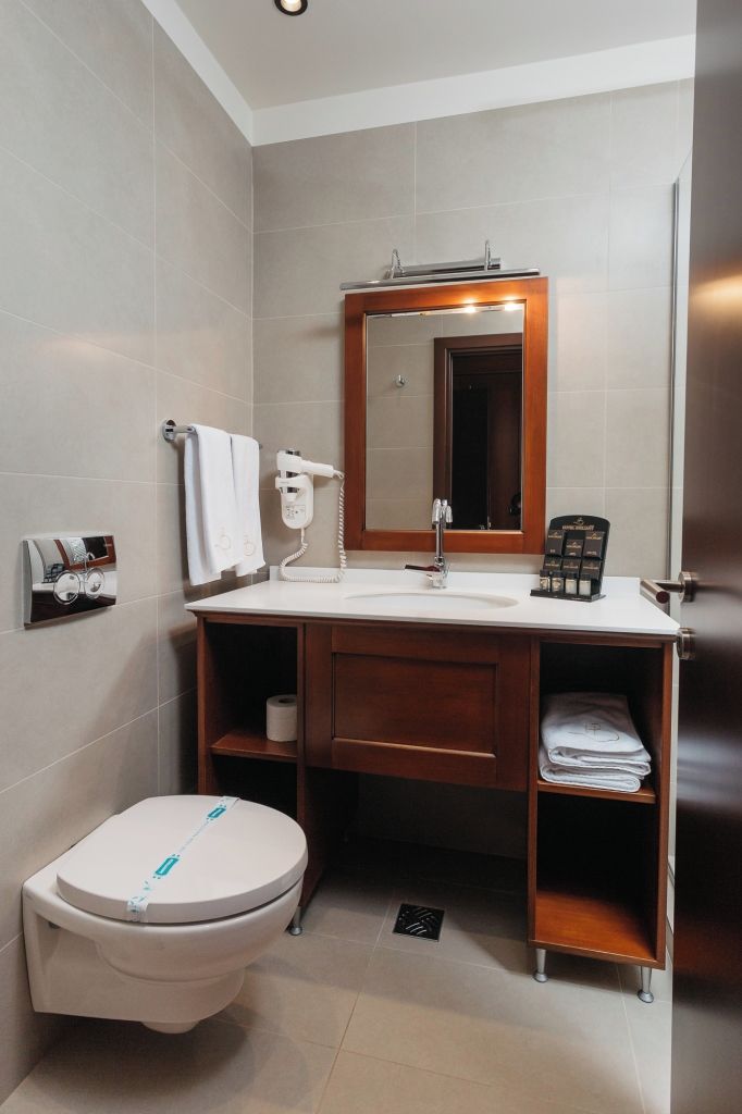 Un baño moderno con inodoro, lavamanos y espejo.