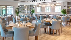 Een ruime restaurantruimte met verschillende zithoeken, houten vloeren en grote ramen voor natuurlijk licht.
