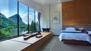 Habitación de hotel moderna con un ventanal amplio que ofrece vistas a un lago y montañas.