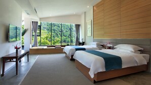 Una habitación de hotel moderna con dos camas, un gran ventanal con vistas a un bosque, un cabecero de madera y una pequeña mesa con un florero.