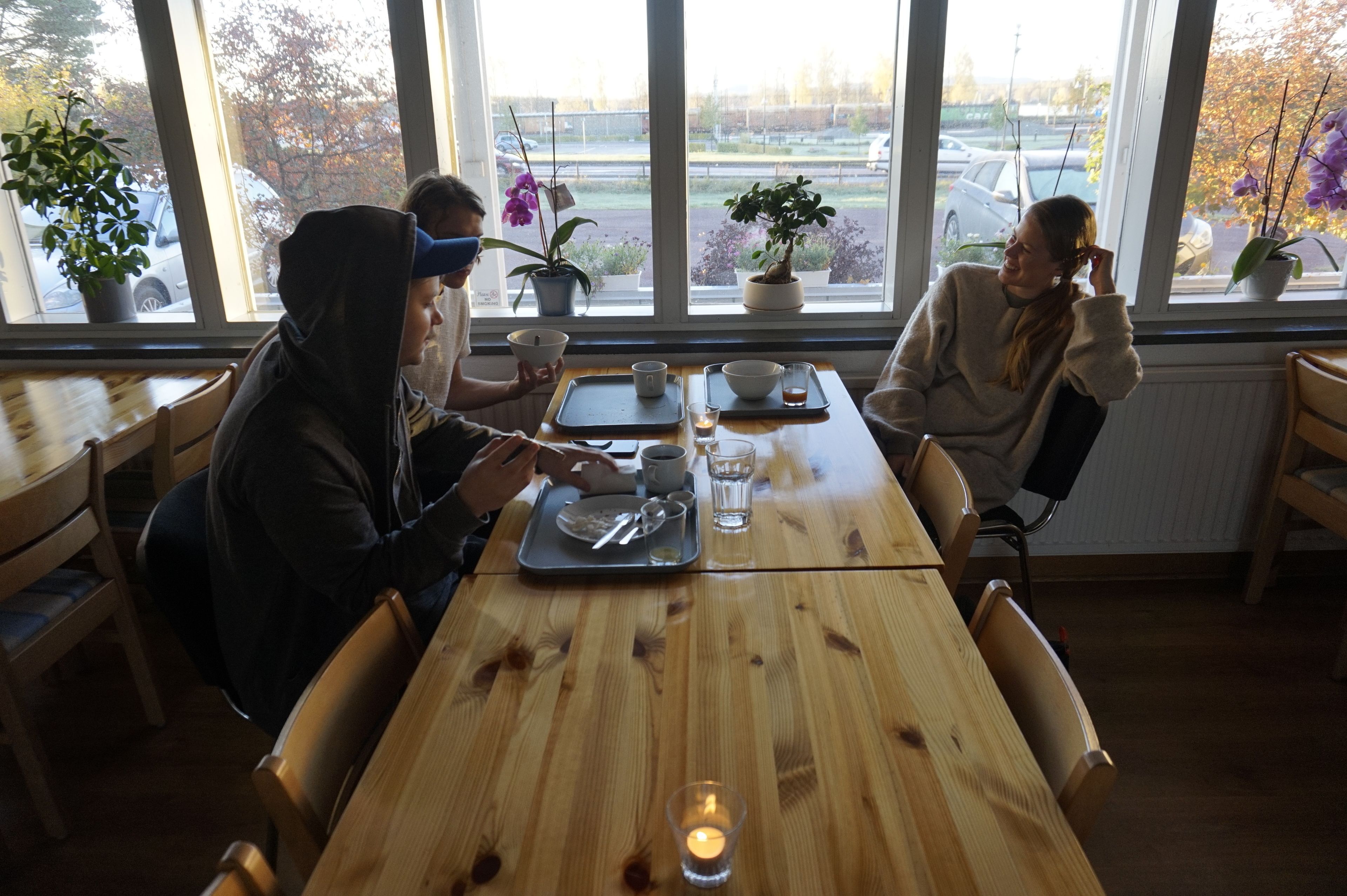 Een houten tafel met een kaars, een dienblad met een kopje en een bloempot.