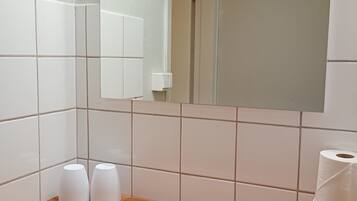 Un baño con azulejos blancos, una encimera de madera y un espejo.