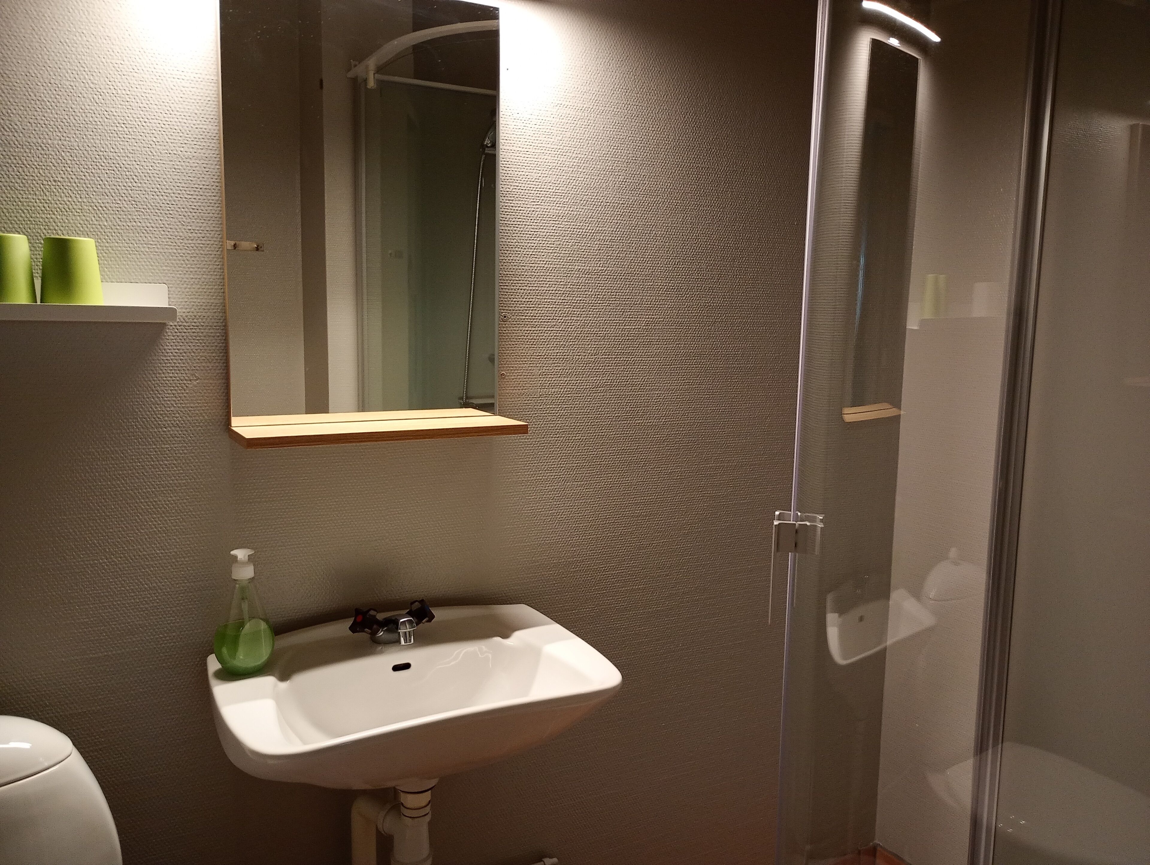 A bathroom with a white sink, a mirror, and a glass shower enclosure.