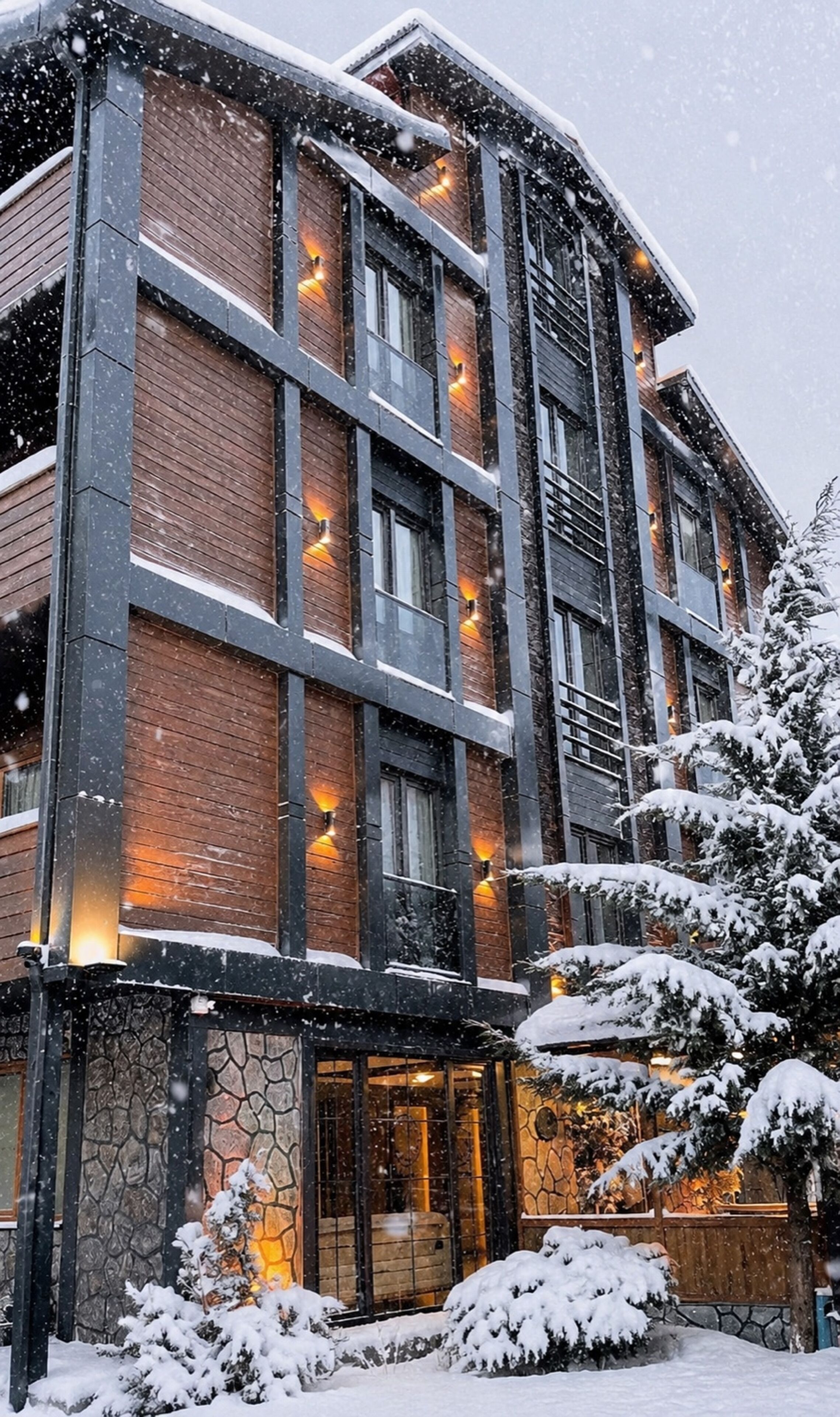 Un edificio de varios pisos con fachada de ladrillo, ventanas grandes y una entrada de piedra. Se ve nieve en el suelo y en los árboles.