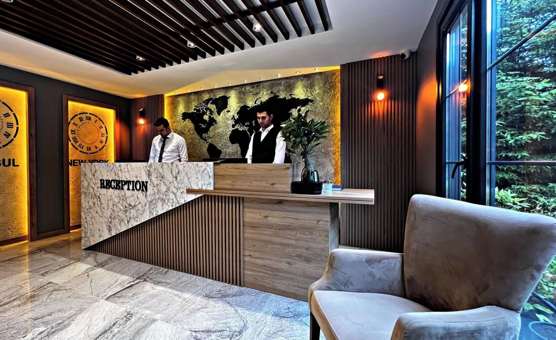 A reception desk with a marble top, a world map mural, and a large window with a view of greenery.