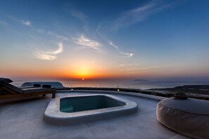 A rooftop terrace with a hot tub, lounge chairs, and a sunset view. - Villa Vinea (Santorini)